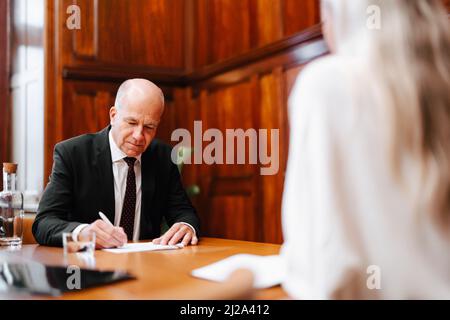 Un homme d'affaires senior signe un contrat avec un conseiller financier dans la salle de réunion du conseil Banque D'Images