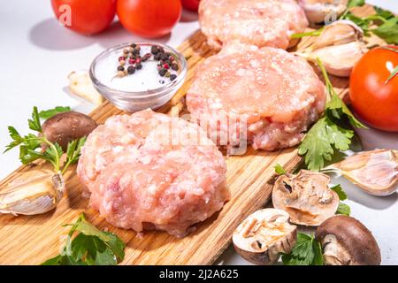 Côtelettes hamburger de poulet, viande hachée de dinde. Patty crue hachée de viande blanche coupée sur une planche à découper avec des épices, des herbes pour la cuisson Banque D'Images