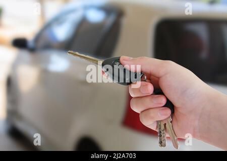 La main de la femme appuie sur la commande à distance des systèmes d'alarme de voiture Banque D'Images