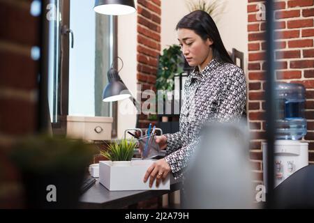 Bouleverser l'employé du bureau de l'entreprise qui a recueilli des objets personnels après avoir été congédié par le chef de l'organisation. Une employée de l'entreprise met ses choses dans une boîte en carton après avoir été tirée. Banque D'Images