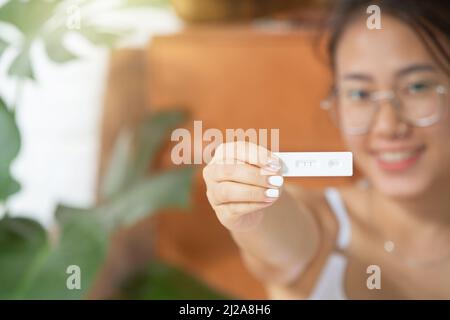 femme caressant son ventre tout en se tenant contre un fond blanc Banque D'Images