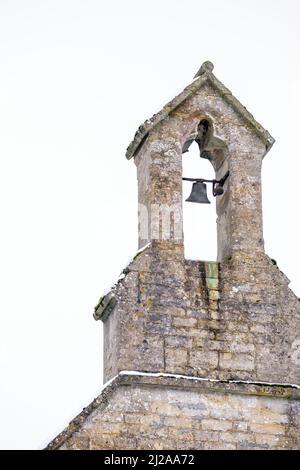 Une jeune femme prend des photos avec son téléphone d'un bonhomme de neige construit sur un banc de parc dans le parc Abbey Grounds à Cirencester Banque D'Images