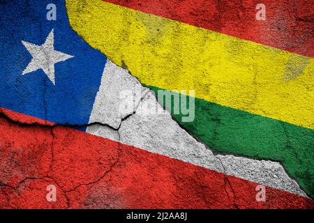 Photo plein cadre des drapeaux altérés du Chili et de la Bolivie peints sur un mur fissuré. Notion de conflit frontalier et de conflit au Chili et en Bolivie. Banque D'Images