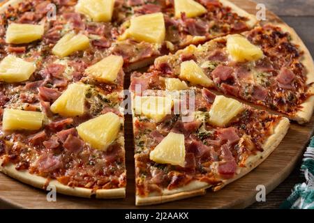 Pizza hawaïenne à l'ananas, au jambon et au fromage sur une table en bois Banque D'Images