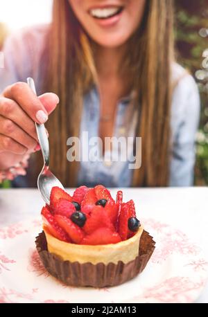 Jeune femme qui goûte un gâteau à la fraise, foyer sélectif. Banque D'Images