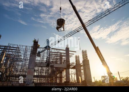 Un travailleur de la construction contrôle une pompe à béton coulé, y compris des grues sur le chantier. Banque D'Images