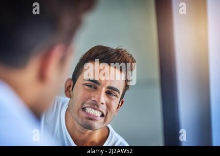 Dents en état de menthe. Photo d'un jeune homme charmant en admirant ses dents fraîchement brossées dans le miroir de la salle de bains. Banque D'Images