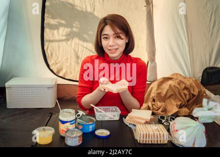 Une femme voyageur prépare des sandwichs pour son dîner à l'intérieur de la tente. Banque D'Images