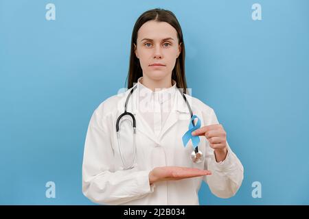 Portrait de la jeune femme calme médecin en robe médicale blanche avec ruban de conscience bleu, symbole de la Journée mondiale du diabète, regardant la caméra, posant isolé Banque D'Images