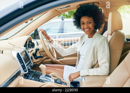 Mettre les choses en marche. Portrait d'une jeune femme d'affaires gaie assise dans le siège conducteur d'une voiture sur son chemin pour travailler pendant la journée. Banque D'Images