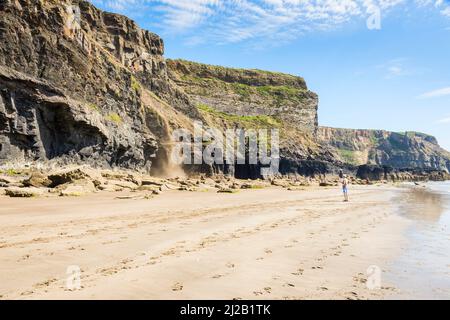 Un homme regarde de la plage comme des rochers et de la terre glissent sur la falaise lors d'une journée ensoleillée à Druidstone dans Pembrokeshire, pays de Galles. Banque D'Images