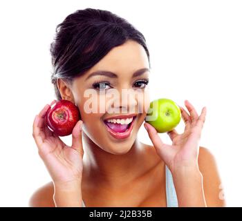 Shes dans une saine alimentation. Une jeune femme en tenue de gymnastique tenant deux pommes et souriant à la caméra. Banque D'Images