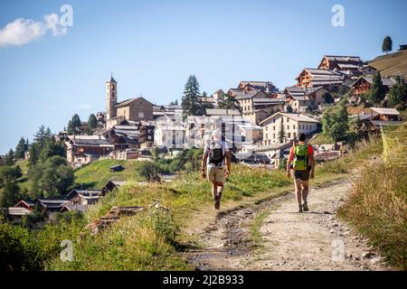 Saint-Veran (sud-est de la France) : deux randonneurs vus de derrière, marchant sur un chemin menant au village, dans le Parc naturel régional du Queyras Saint- Banque D'Images