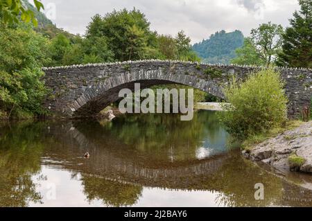 Le pont en pierre à cheval voûté de Grange à Borrowdale, dans le district du lac anglais, se reflète dans la rivière Derwent. Le sommet caractéristique de C Banque D'Images