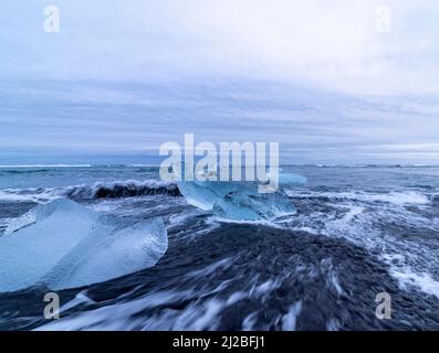 Petits blocs de glace et vagues sur Diamond Beach avec sable noir, Breidamerkursandur, Islande Banque D'Images