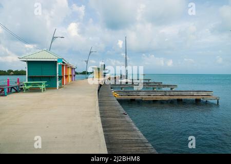 Huttes colorées au quai en bois du port de Placencia, Belize Banque D'Images