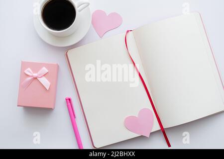 vue de dessus du carnet avec coeurs en papier et une tasse de café près de l'enveloppe sur blanc Banque D'Images