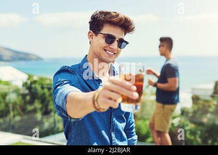 C'est toujours un bon moment pour un toast. Portrait d'un beau jeune homme levant son verre pour un toast tout en se relaxant dehors avec ses amis. Banque D'Images