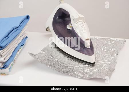 Le fer refait repasser la feuille sur un fond blanc. Nettoyage de la semelle du fer des dépôts de carbone par des méthodes populaires. Banque D'Images