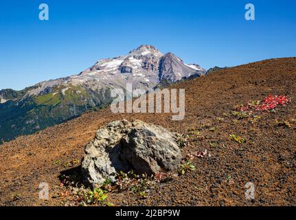 WA21237-02...WASHINGTON - un rocher erratique logé dans le côté de la Chuck White Cinder Cone avec Glacier Peak au loin, une partie de la Glacie Banque D'Images