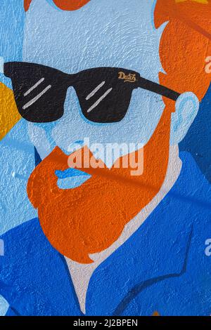 Portrait d'un gars avec cheveux orange et barbe portant des lunettes de soleil noires peintes sur un mur d'une barre à Willemstad, Curaçao Banque D'Images