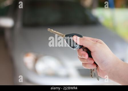 La main de la femme appuie sur la commande à distance des systèmes d'alarme de voiture Banque D'Images