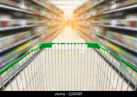 chariot avec fond flou de bouteilles de vin sur les étagères de boissons alcoolisées dans le supermarché Banque D'Images