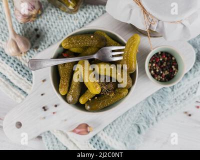 Conserver les concombres marinés, les assaisonnements et l'ail sur une table en bois blanc Banque D'Images