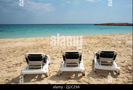 Plage tropicale de sable vide avec chaises longues décontractées Banque D'Images