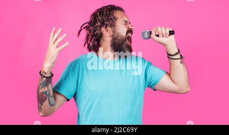 Homme barbu chantant avec microphone. Beau gars en t-shirt bleu Sing en karaoké. Concept de musique. Banque D'Images