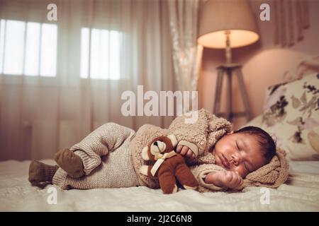 Bébé multiethnique bébé garçon dormant sur un lit. Aspect confortable avec ours en peluche Banque D'Images