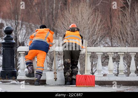 Deux concierges avec des pelles sur le fond des arbres du parc. Travailleurs migrants pendant le repos, nettoyage des rues au printemps, déneigement Banque D'Images