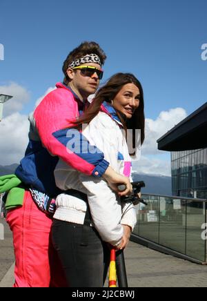Le Jeune couple en costume de sport vintage à cheval électrique dans le centre-ville de Vancouver, Colombie-Britannique, Canada Banque D'Images
