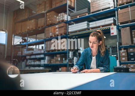 Jeune femme travaillant dans un lieu de travail industriel Banque D'Images