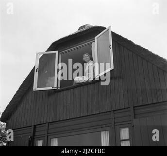 SEPHA van Beinum-Janssen, épouse du chef d'orchestre Eduard van Beinum, est assise sur le rebord de la fenêtre devant une fenêtre ouverte de leur maison de campagne Bergsham à Garderen ca: 5 juin 1954 Banque D'Images