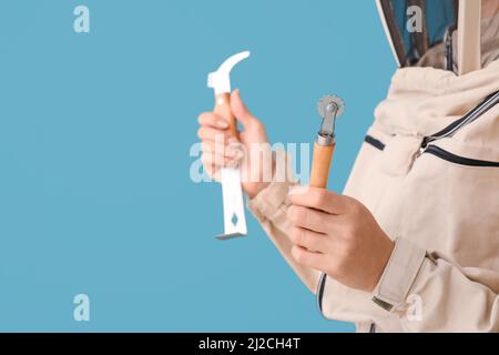 Femme gardienne en costume de protection avec outils sur fond bleu, gros plan Banque D'Images