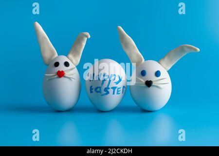Composition de Pâques avec œufs de Pâques décorés de fleurs et lapin de Pâques. Arrière-plan bleu, espace de copie. Banque D'Images