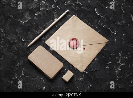 Photo de l'enveloppe vintage vierge et de la papeterie sur fond de plâtre noir. Banque D'Images