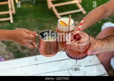 Un cliché sélectif de mains tenant différents types de boissons dans le jardin Banque D'Images