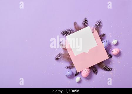 Une maquette d'une enveloppe rose avec des œufs et des plumes de Pâques Banque D'Images