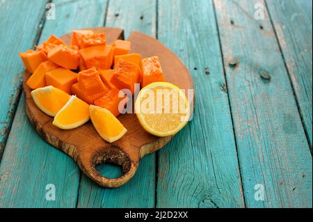 Courge musquée douce, orange et citron coupé sur panneau en bois sur table turquoise copyspace Banque D'Images