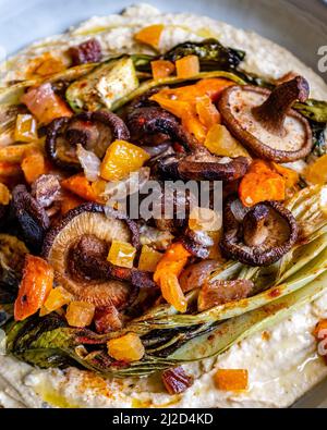 Gros plan de houmous avec légumes rôtis dans une assiette blanche Banque D'Images