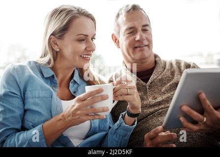 Selon vous, que devrions-nous utiliser ce profil pic. Photo d'un couple d'âge mûr avec une tablette numérique tout en se relaxant sur le canapé à la maison. Banque D'Images