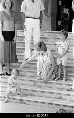 HRH la princesse Diana, la princesse de Galles et son mari HRH le prince Charles, le prince de Waleson vacances à Palma, Majorque. Ils sont les invités du roi Juan Carlos (à droite - presque hors de vue) et de sa femme Sofia (à gauche), et sont photographiés ici au Palais Marivent, Palma, Majorque. Dans cette photo, la princesse Diana aide son fils de près de 2 ans, le prince Harry gérant les étapes. Son frère aîné, le Prince William, regarde. Photo prise le 9th août 1986 Banque D'Images