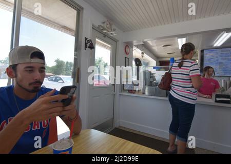 Un jeune homme au bord de Gen Z textes à l'intérieur d'un restaurant Dairy Queen à Cissna Park, Illinois Banque D'Images