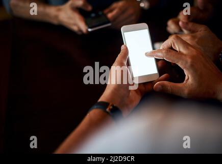 Vérification de nos boîtes de réception ensemble. Gros plan sur un homme méconnu qui envoie un message texte sur son téléphone tout en étant assis à l'intérieur d'un bar la nuit. Banque D'Images