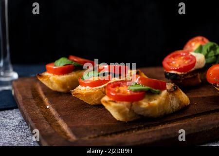 Bruschetta typiquement italienne ou tapa espagnol avec tomates cerises, basilic et fromage à tartiner de type Philadelphie. Concept alimentaire méditerranéen. Copier l'espace. Banque D'Images