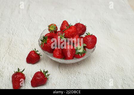 Fraises mûres dans un bol en cristal qui se tient sur une table blanche Banque D'Images