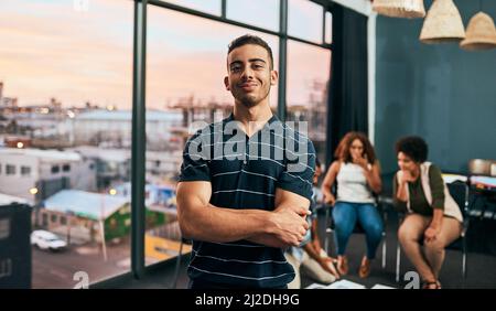 Il a de grands rêves pour leur petite entreprise. Portrait d'un jeune homme joyeux debout avec ses bras pliés avec ses collègues de travail regroupés Banque D'Images