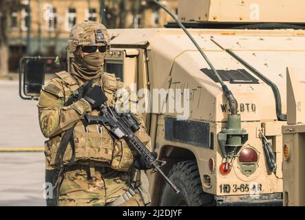 États-Unis - Mars 29 2022: Soldat du corps des Marines des États-Unis avec visage couvert et lunettes de soleil, fusil de chasse et véhicule blindé humvee dans la ville, États-Unis Banque D'Images